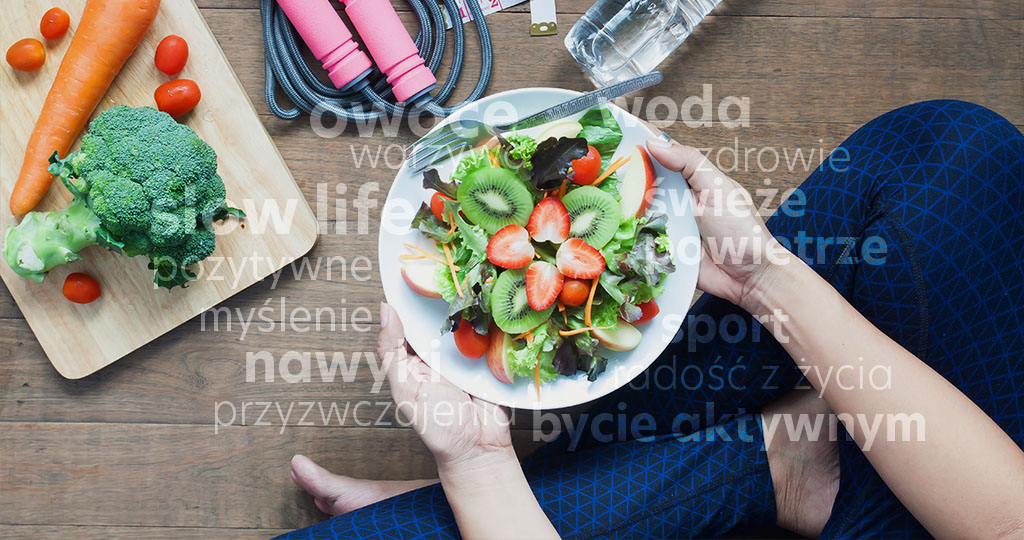 Zdrowy styl życia, siedząca kobieta trzyma w rękach talerz pełen odżywczej sałatki skomponowanej ze świeżych warzyw i owoców